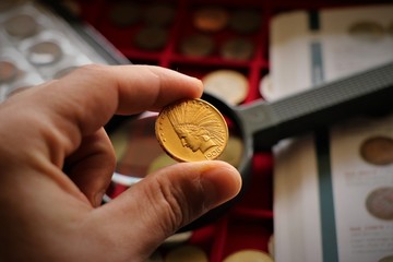 Numismatic at work shows some gold coins. Accessories are visible in the background.