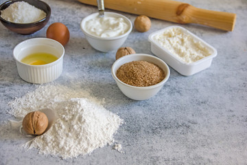 Fototapeta na wymiar Ingredients for baking - raw egg, flour, brown sugar, nuts, soft cheese on a stone background