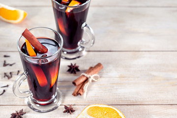 Mulled wine with cinnamon, orange fruit and anise stars on wooden background, copy space.