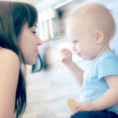 beautiful mother playing with her beautiful child , the child eats the cookie and laughs