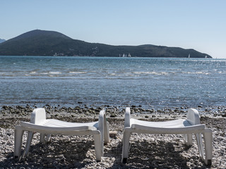Two white plastic chaise lounge on sea side