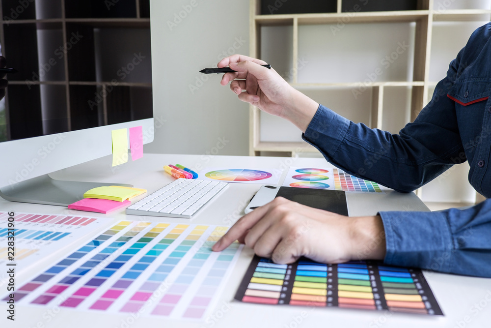 Poster male creative graphic designer working on color selection and color swatches, drawing on graphics ta