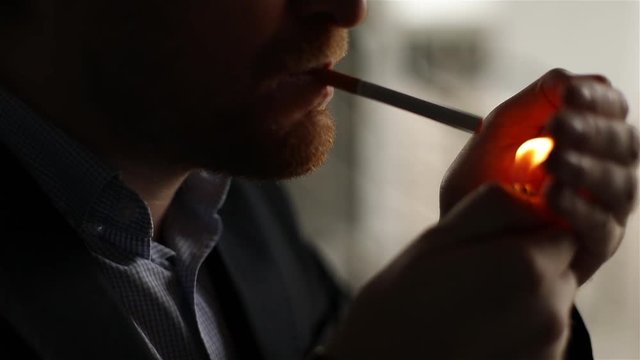 Attractive man with glasses smoking cigarette. Silhouette, slow motion