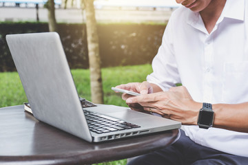 Image of businessman working with laptop and analysis financial document data on smartphone in outdoor office, finance,investment, business concept and Accounting,Economic,commercial
