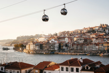 Old town of Porto on Douro River with cable cars and boats at sunset, Portugal.