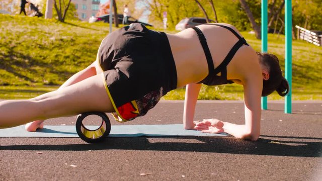Woman doing self massage of the legs with a roll. Sunny day, golden autumn