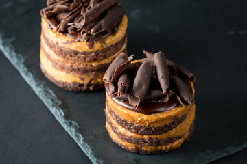 Chocolate cakes on black slatter board with mint, coffee beans on dark background, closeup photo. Fresh, tasty dessert food concept. 