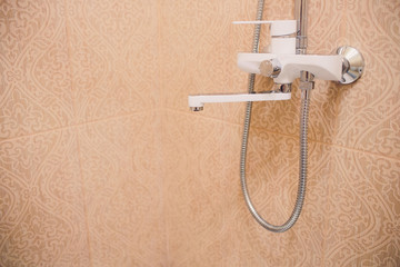 In the bathroom, open shower mixer has attached to the wall bracket, tinted black and white image,...