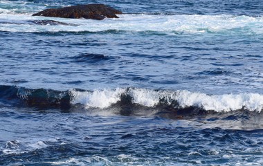  view of a wave with white caps on the blue ocean surface, rolling towards the shore
