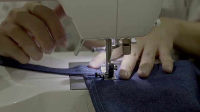 Close up footage of a woman sewing a apron with a sewing machine