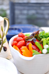 Fresh vegetable salad in a cup on the dining table. Ingredients for summer salad. Vitamins and benefits. Copy space.