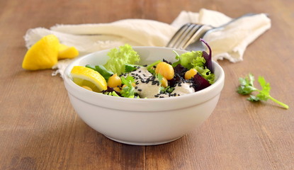 Healthy salad with chickpeas, beets, greens mix and yogurt-garlic sauce