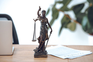 close-up view of lady justice statue, contract and laptop on table
