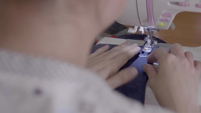 Close up footage of a woman sewing a apron with a sewing machine