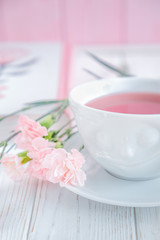 Fruit tea in white cup and pink carnation flowers on a white background. Free space