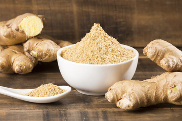 Fresh roots and ginger powder - Zingiber officinale. Wooden background