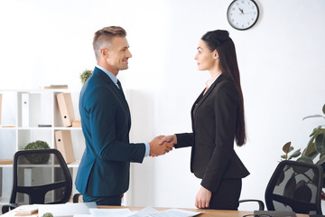 side view of business colleagues shaking hands at workplace in office