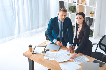 high angle view of business colleagues doing paperwork at workplace in office