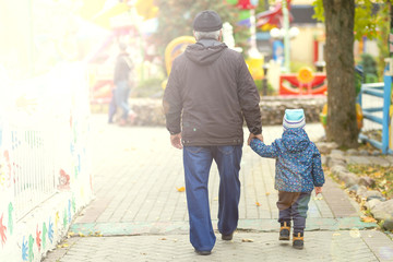 grandfather and grandson walk together in the park