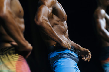 athlete bodybuilder in blue summer shorts at competitions in beach bodybuilding