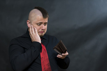 Punk. Dark shirt and red tie. In the left hand open wallet. Right hand holding his head. On the...