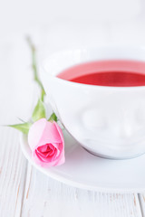 Fruit tea in white cup and pink rose on a white background. Free space