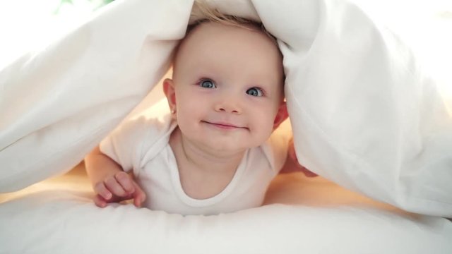 Cute baby girl lying on white sheet at home