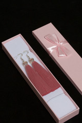 Earrings made of viscose handmade. Together with wrapping gift boxes. Against the black background.