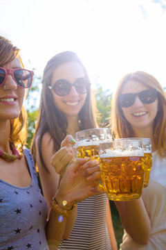 Group of young women enjoying outdoors with beer.