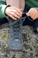 Kind bindet alleine die Schnürsenkel der Schuhe
