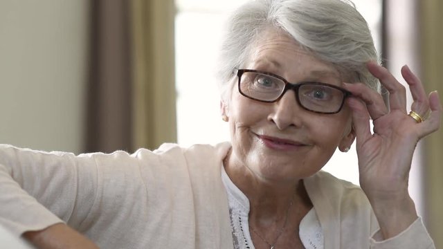 Senior woman holding eyeglasses and smiling