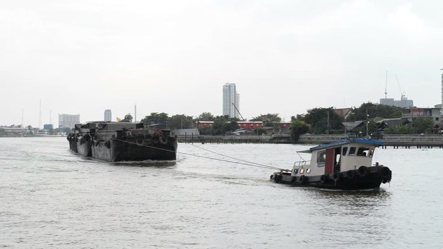 The tug boats towing a big barge with sand. Cargo ship in a river.