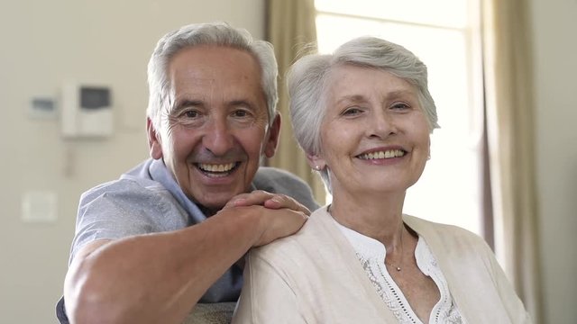 Happy senior couple smiling and looking at camera indoor