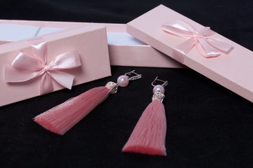 Earrings made of viscose handmade. Together with wrapping gift boxes. Against the black background.