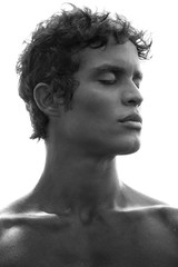 Profile portrait of a fit, bare-chested man with black hair and strong features in black and white