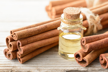 cinnamon oil and cinnamon sticks on the wooden board