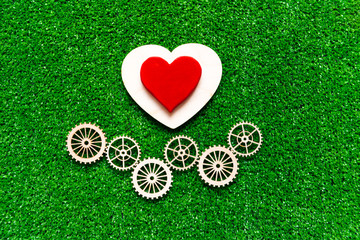heart, gears on the background of artificial green grass. love, mechanism, interaction.