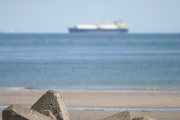 浜辺の消波ブロックと水平線上の船