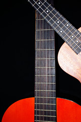 Fototapeta premium Guitar on black background. Musical hobby. The neck of the guitar. Ukulele. Strings. Musical instruments.