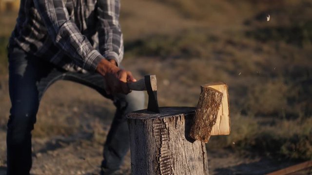 man splits logs with an ax