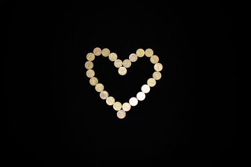 Money heart on a black background. Symbol of money. Copper coin. Trifle. Ten-Ruble Coins. Love of money. Prosperity and wealth. Abundance and prosperity.