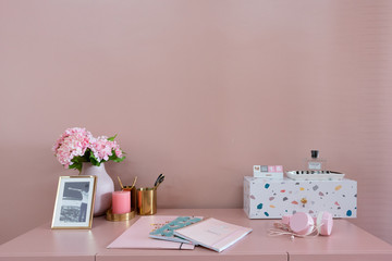 Working corner with white and multicolor pebbles terazzo cabinet on baby pink working top with old rose painted wall in the background / interior design concept / interior for advertising