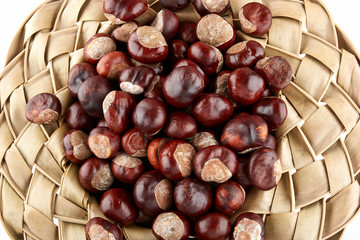 Wicker hat filled with chestnuts. Peeled horse-chestnuts