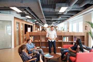 Casually Dressed Businessmen And Businesswomen Having Informal Meeting In Modern Office
