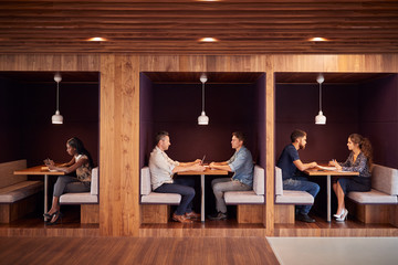 Casually Dressed Businessmen And Businesswomen Meeting And Working In Cubicles In Modern Office