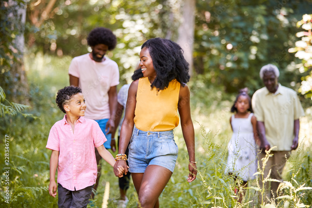 Wall mural black mother and son walking in woods looking at each other