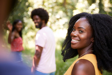 Young black woman in a forest with friends turning to camera