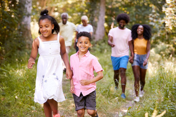 Fototapeta premium Two kids ahead of their family during a walk in a forest