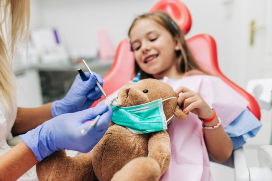 Cute little girl sitting on dental chair and having dental treatment.