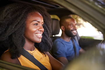 Fototapeta na wymiar Young black couple smiling in a car during a road trip